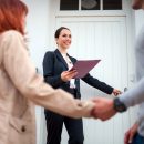 Real estate agent near door inviting young couple to enter house for visit